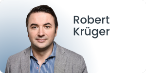 Auf der linken Seite des Bildes ist eine Person zu sehen, die einen grauen Blazer und ein blau gestreiftes Hemd trägt. Der Hintergrund ist ein Farbverlauf von Hellblau zu Dunkelblau. Der Text auf der rechten Seite lautet Robert Krüger.