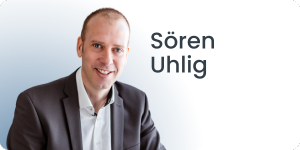 Vor einem weißen Hintergrund lächelt eine Person im Anzug in die Kamera. Daneben ist der Text „Sören Uhlig“ zu sehen.