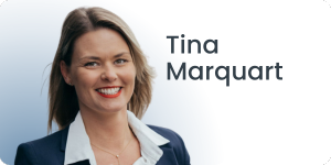 Eine Frau mit schulterlangem Haar lächelt. Sie trägt einen marineblauen Blazer und eine weiße Bluse. Der Hintergrund ist ein Farbverlauf von Hellblau nach Weiß, auf dem rechts in dunkler Schrift der Text Tina Marquart steht.
